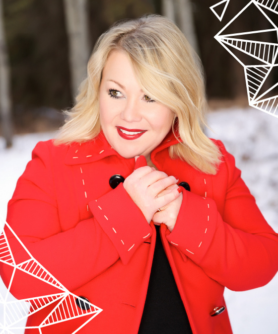 Jann Arden in a red coat in a snowy forest